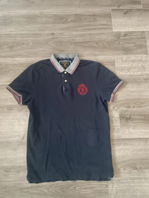 Mörkblå pikétröja från Bondelid - Säljer en mörkblå pikétröja från Bondelid med grå krage och röda detaljer. Den är i mycket bra skick och sparsamt använd. Storlek S, diskutera gärna pris✅