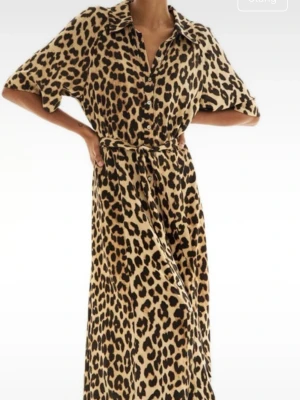Leopardmönstrad långklänning XS - Säljer en snygg långklänning från H&M i leopardmönster. Klänningen har knappar framtill, krage och ett matchande midjebälte. Tillverkad i 100% viskos som känns lätt och skön mot huden. Perfekt för dig som vill sticka ut med ett djuriskt print.