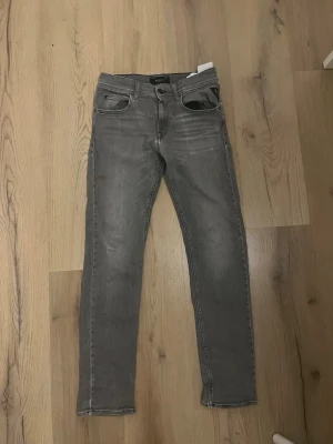 Replay jeans - Snygga grå jeans från Replay, modell Wallys. De har klassisk femficksdesign, raka ben och diskreta slitningar framtill. Jeansen är tillverkade i mjukt bomullsmaterial med en modern, slim passform. Perfekta för dig som gillar stilrena och coola jeans.
