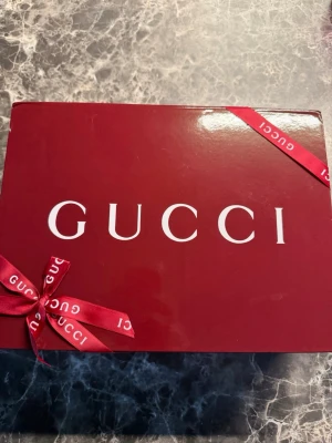 Svart axelväska från Gucci - Säljer en stilren svart axelväska från Gucci med diskret mönster och silverfärgad dragkedja framtill. Väskan är tillverkad i skinn och har en elegant struktur på ytan. Kommer med original dustbag och presentask. Perfekt för dig som gillar lyxiga detaljer.