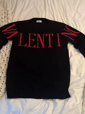 Valentino Stickad tröja svart - Svart stickad tröja från Valentino med stor röd logga över bröstet och armarna. 995kr