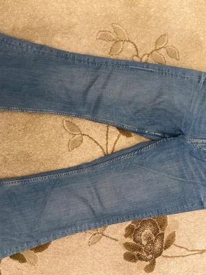 Blå flare jeans från &Denim, strl 40 - Säljer ett par ljusblå flare jeans från &Denim i storlek 40. Modellen har ultra hög midja och klassisk femficksdesign. Jeansen är tillverkade i mjukt denimtyg och har en snygg utsvängd siluett som ger en cool retro vibe.