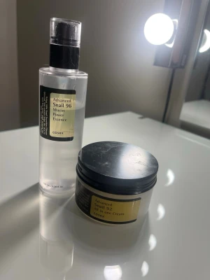 COSRX Snail 96 Essence & Snail 92 Cream - Säljer två populära hudvårdsprodukter från COSRX: Advanced Snail 96 Mucin Power Essence i genomskinlig pumpflaska och Advanced Snail 92 All in one Cream i vit plastburk med svart lock. Båda innehåller snigelsekret för återfuktning och glow. Om man bara vill köpa en kostar det 115 st.