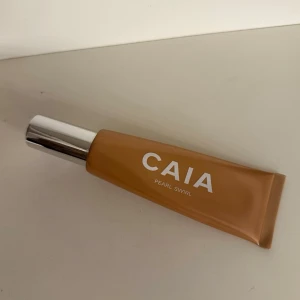 CAIA Pearl Swirl highlighter - Flytande highlighter från CAIA i nyansen Pearl Swirl. Kommer i en brun tub med silvrig pump och lock. Perfekt för att ge ansiktet en glowig finish och framhäva kindbenen. Tuben är smidig att ta med och enkel att använda.