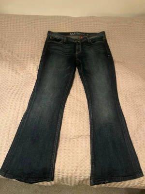 Low waist jeans från Guess - Snygga mörkblå jeans från Guess, modell Melrose Flare. De har klassisk design, är flared i benen och har kontrastsömmar. Jeansen är tillverkade i slitstarkt denimtyg och har en cool vintage-look med lätt tvättade detaljer.