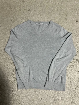Grå V-ringad tröja från Dressmann Storlek M - Grå stickad tröja från Dressmann. V-ringad och mjuk i materialet. Passar bra till vardags eller jobb. Storlek S. Bra skick, inga hål eller fläckar. Lätt att matcha.                                                 Skickas snabbt, hör av dig vid frågor eller om du vill ha fler bilder! 