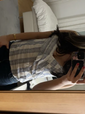 Randig linnetopp från H&M  - Säljer en fräsch vit och blå randig linnetopp från H&M gammal kollektion. Toppen har smala axelband, omlott-detalj framtill och är tillverkad i ett lätt och luftigt bomullsmaterial jätte skön och sitter perfekt, perfekt för varma dagar och enkel att matcha med jeans eller shorts!!! storlek 42 men jag själv är 32/34 och den sitter väldigt bra på mig 