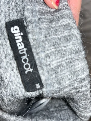 Grå stickad tröja från Gina Tricot - Mysig grå stickad tröja från Gina Tricot i storlek XS. Tröjan har en rund halsringning och kortärmade ärmar, perfekt för kyliga dagar. Den har en loose passform och är enkel att matcha med jeans eller kjol.