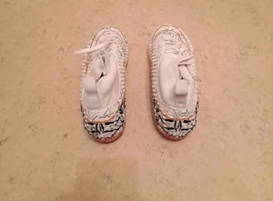 Unika vita fotbollsskor med guldmönster - Säljer ett par fotbollsskor i vitt med coolt spräckligt mönster i svart, guld och färgdetaljer. Skorna har snörning, platt sula med dobbar och rund tå. Ovandelen är i syntetmaterial och har en stickad sockliknande krage för extra komfort. Perfekt för dig som vill sticka ut på planen. 