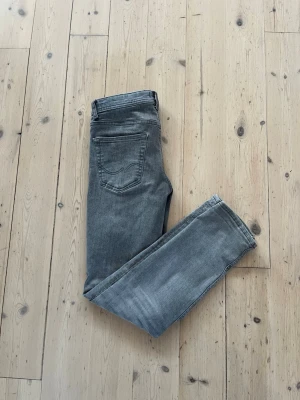 Jack & Jones slim fit jeans grå - Snygga blå jeans från Jack & Jones, modell Slim Glenn. Storlek 29W 30L. Jeansen har en slim passform, klassisk femficksdesign och är tillverkade i stretchig denim för extra komfort. Jeansen är i bra skick och de har en fet wash. Perfekta för dig som gillar en smal siluett och stilren look. Jag är cirka 170 och kan fortfarande ha dem. De är storlek 158 men passar större.