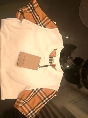 Burberry t shirt - Snygg burberry t shirt. Helt ny, säljs för bra pris. Perfekt för sommaren om man vill sticka ut. Har lite elastiskt material. Storlek S. Hör av vid frågor!!