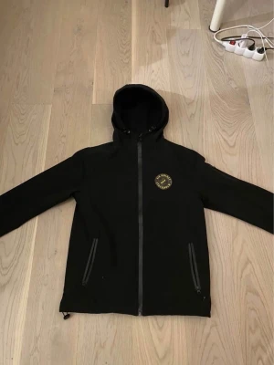  AIK Hockey jacka - Svart vindjacka med AIK Hockey Stockholm-logga på bröstet. Använd fåtal gånger och inga tecken på användning. Storlek SMALL