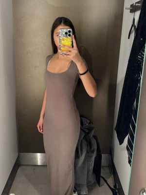 Brun beige ribbad långklänning  - Säljer en brun beige ribbad långklänning från newyorker med korta ärmar och fyrkantig ringning. Klänningen har en tight passform och är tillverkad i ett mjukt, stretchigt material som sitter snyggt på kroppen. Den går ända ner till fötterna på mig och jag är ca 160cm lång ❤️använt 1 gång. 