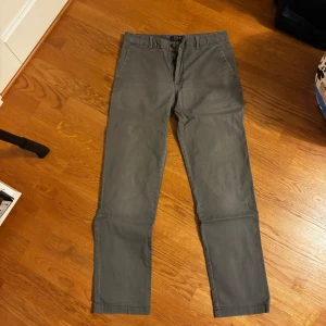Grå chinos från Polo Ralph Lauren - Snygga grå chinos från Polo Ralph Lauren med raka ben och klassisk passform. Byxorna har bälteshällor, sidofickor fram och två bakfickor med knapp. Tillverkade i mjuk bomull som känns skön mot huden. Perfekta till en clean och stilren look.