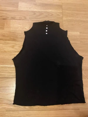 Svart ärmlös topp med silvriga nitar - Säljer en svart ärmlös topp med hög hals och fyra silverfärgade fyrkantiga nitar framtill. Ingen strl står men gissar på S. Perfekt till nyår!!