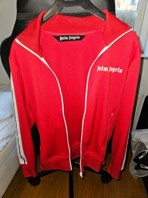 Röd Palm Angels tracksuit med dragkedja - Säljer en röd Palm Angels tracksuit I storlek S. Använder den helt enkelt inte längre kvitto finns från farfetch och certilogo qr+clg kod funkar. Den är i väldigt bra skick. 
