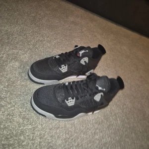 Svarta Nike Jordan 4 sneakers - Säljer ett par svarta Nike Jordan 4 sneakers med grå och vita detaljer. Toppskick aldrig använt.