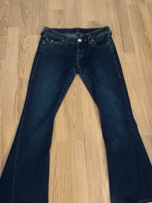 True Religion Joey Low Rise Flare Jeans - Säljer ett par mörkblå True Religion Joey Low Rise Flare jeans i storlek 26. De har låg midja, klassisk femficksdesign och utställda ben med snygga kontrastsömmar inte alls använda mycke eftersom de då inte passade just mig.❤️har också sytt upp dom skriv till mig om man har fler frågor t.e.x hur långt o sånt!