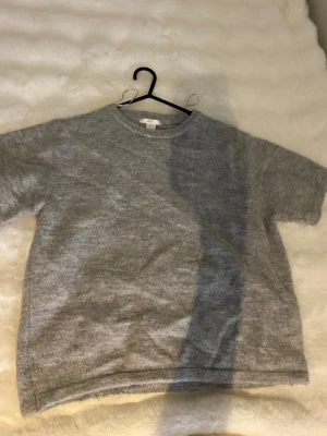 Grå stickad tröja Gina Tricot - Säljer en enkel och snygg grå stickad tröja från Gina Tricot. Tröjan har korta ärmar, rund hals och är tillverkad i mjukt stickat material. Perfekt för dig som gillar en clean och chill stil.