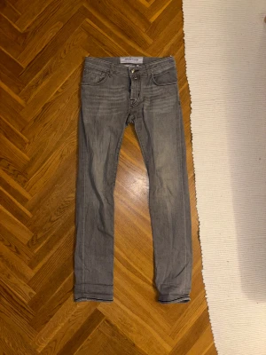 Grå jeans från Jacob Cohën - Snygga grå jeans från Jacob Cohën med klassisk femficksdesign och silverfärgad knapp. Jeansen har smal passform och raka ben, tillverkade i mjuk bomullsdenim. Perfekta för dig som gillar stilrena och moderna jeans med diskret tvätt.