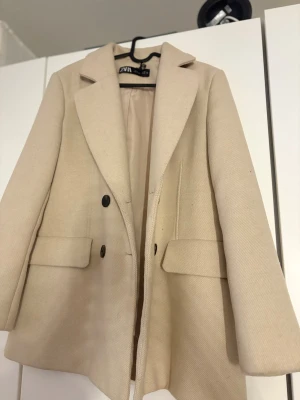 Beige kappa/kavaj från Zara - Detta är en kappa/kavaj ifrån Zara. Den är använd några gånger men är fortfarande jättefin och kvaliteten är perfekt på den!