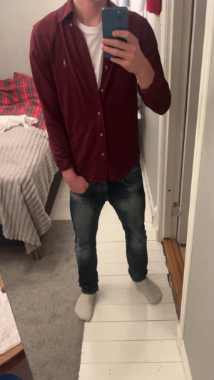 Vinröd skjorta från Ralph Lauren - Vinröd skjorta från Ralph Lauren, modell Knit Oxford. Klassisk design med knappar framtill och broderad logga på bröstet. Skjortan har lång ärm och normal passform. Materialet är mjuk bomull som känns skönt mot huden. Perfekt för dig som gillar stilrena plagg med premiumkänsla. Den får dig att stå ut med lugn stilrenhet😉 hör av dig vid funderingar 😁😁