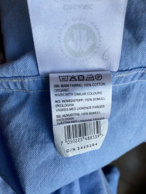 Blå slim fit skjorta från Dressmann -storlek Medium  - Fräsch ljusblå skjorta från Dressmann i slim fit-modell. Skjortan är tillverkad av 100% ekologisk bomull och har klassisk krage med knappar, bröstficka och långa ärmar med manschettknappar. Perfekt för dig som gillar stilrena och enkla plagg.