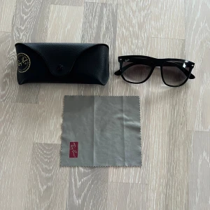 Ray-Ban boyfriend solglasögon - Klassiska svarta Ray-Ban boyfriend solglasögon med bred båge och mörka glas. Säljs med originalfodral i svart skinn och putsduk med Ray-Ban-logga. Perfekt accessoar för en cool och tidlös stil.
