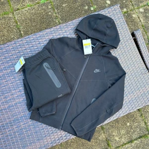  Nike tech new season - Nike hoodie i svart med huva och hel dragkedja framtill. Snygg, stilren design med Nike-logga på bröstet och praktiska fickor med dragkedja. Perfekt för chill eller träning, tillverkad i mjukt bomullsmaterial för skön komfort.