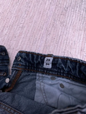 Jack & Jones jeans  - Säljer ett par Jack & Jones Relaxed Chris jeans i klassisk blå tvätt. Modellen har avslappnad passform, raka ben och fem fickor. Jeansen har orangea sömmar och är tillverkade i slitstarkt denimtyg. Perfekt för dig som gillar en chill och enkel stil.