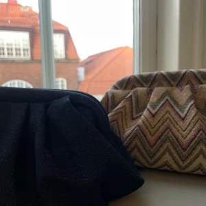 Clutch bag - Jag säljer egengjorda clutch bags i zigzag-mönster och denim. Just denna annons är för den zigzag som går i beige, rosa och grå toner. Väskan stängs med metallklämma. Insidan är fodrad i vinrött tyg och rymmer småsaker som smink och plånbok☺️Om du är mer intresserad av den i denim tyg så släng iväg ett meddelande så fixar vi det! Vill du ha bilder med väskan till en outfit så hör av dig! Bra att veta är att den i denim tyg kostar 349 och den i zigzag 399!