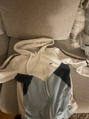 Lacoste zip hoodie sällsynt  - En cool blå och mörk blå och vit hoodie som sticker ut i mängden och denna kofta är perfekt för dig som vill sticka ut i mängden och ha en bra och unik look