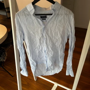Ljusblå linneskjorta från Zara Man - Fräsch ljusblå skjorta från Zara Man i slim fit-modell. Tillverkad i linne, med klassisk krage och knappar framtill. Långärmad och perfekt för dig som gillar en clean och stilren look. Skjortan har en lätt och luftig känsla, perfekt för varmare dagar.
