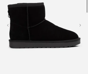 Svarta boots - Svarta boots med rund tå och platt sula i mjuk mocka. Skorna har en klassisk, enkel design med kort skaft och synliga sömmar. Perfekta för kalla dagar när du vill ha både stil och komfort.