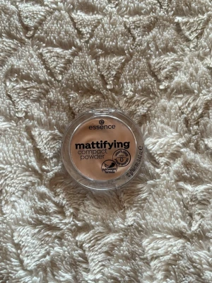 Essence mattifying compact powder - Mattifying compact powder från Essence i färgen 11 Pastel Beige. Puder i rund plastförpackning med transparent lock. Ger en matt finish och har en ljus beige ton som passar för att fixera foundation och minska glans. Smidig att ha med i väskan för touch-ups under dagen.