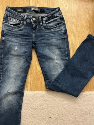 Mörkblå bootcut jeans från LTB - Snygga mörkblå bootcut jeans från LTB med slitna detaljer och klassisk femficksdesign. Jeansen har låg midja och är tillverkade i stretchig denim för skön passform. Perfekta för en avslappnad och trendig look.