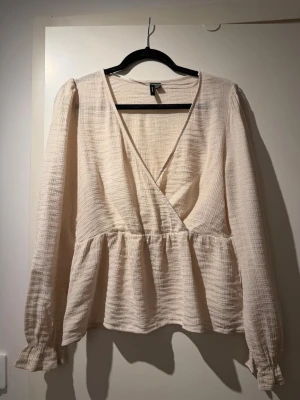 Beige omlottblus med v-ringning - Stilren beige omlottblus från Veromoda med v-ringning och lång ärm. Använd fåtal gånger!
