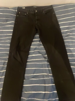 Svarta Jack and Jones jeans - Säljer mina svarta Jack & Jones jeans i storlek 32/32. De har passform: slim/ regular. Köpta för 600 på Jack and Jones, kan gå ner i pris vid snabb affär! Där är i bra skick inga tecken på skador eller defekter!