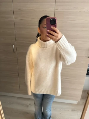  polotröja från H&M - Mysig beige stickad polotröja med oversized passform och breda ribbade muddar vid ärmslut och nederkant. Tröjan har hög krage och är perfekt för kyliga dagar. Passar till jeans eller kjol för en avslappnad look.