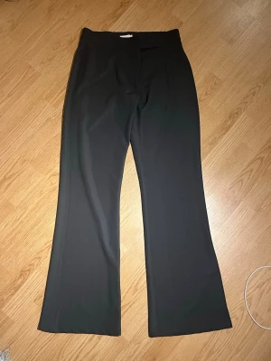 Svarta kostymbyxor - Snygga kostymbyxor. Byxorna har klassisk design och är tillverkade i ett mjukt polyestertyg som ger en dressad look. Perfekta för dig som vill ha en stilren och trendig byxa.