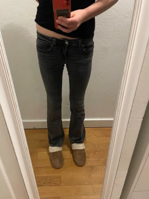 Mörkgrå bootcut jeans låg midja - Säljer ett par mörkgrå bootcut jeans med låg midja. Jeansen har klassisk femficksdesign och är tillverkade i ett mjukt bomullsmaterial med lite stretch. Snygg tvättad look och passar perfekt till en avslappnad stil.