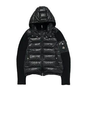 Söker denna i XL !!!!!  - Snygg svart pufferjacka från Moncler med glansig quiltad kropp, stickade ärmar och stor huva. Jackan har dragkedja framtill, fickor med tryckknappar och en ikonisk logga på ärmen. Perfekt för kyliga dagar och riktigt trendig look. 