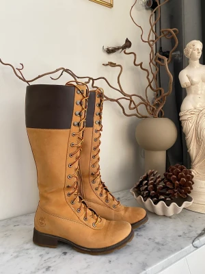 Timberland Classic Tall boots stl 38 – fint skick - Säljer ett par Timberland Classic Tall Lace-Up boots i damstorlek 38. Skorna är använda men i fint skick, med några mindre märken (se bilder), annars i perfekt form för vintern och kalla dagar. Den klassiska Timberland-designen gör dem lika stabila som snygga — redo för både promenader, vardagsbruk och snöiga äventyr.  Nypris ca 1 800 kr  Spana gärna på mina andra annonser så kan vi samfrakta.  (Sökord: Timberland Classic Tall stl 38 dam boo