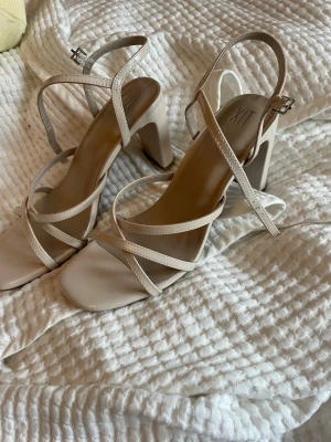 Beige klackskor från XIT - Beige klackar från XIT med smala remmar och fyrkantig tå. Skorna har en stabil hög klack och justerbart spänne vid ankeln. Använda en gång på ett bröllop☀️