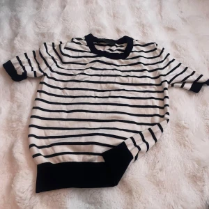 Randig t-shirt från Zara - Säljer en vit och svart randig t-shirt från Zara. T-shirten har korta ärmar, rund halsringning och svarta ribbade muddar vid ärmslut, hals och nederkant. Perfekt för en avslappnad och stilren look. helt ny aldrig använd
