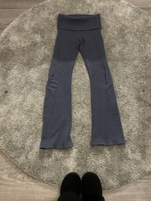 Mörkblå leggings från Gina Tricot - Mörkblå leggings från Gina Tricot med bred ribbad midja och utsvängda ben. Tillverkade i mjukt material som sitter skönt och följer kroppen. Perfekta för en avslappnad och trendig look.