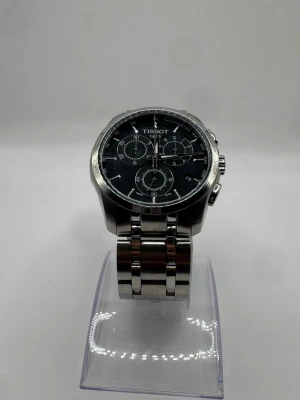 Tissot Couturier Chronograph - Nypris: ca 7 500 kr. Jättebra skick, ser nästan ny ut. Fulla länkar minus 2 original. Med box, utan papper. Elegant svart urtavla, quartz, kronograf – redo att bäras! Pris kan diskuteras vid snabb affär!