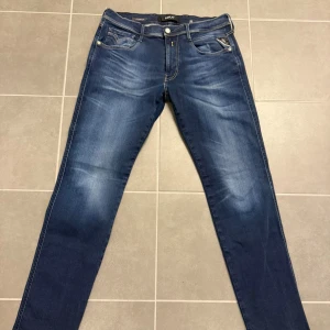 Blå Replay Anbass jeans herr - Säljer ett par snygga blå Replay Anbass jeans med klassisk femficksdesign och kontrastsömmar. Jeansen har normal passform och är tillverkade i mjukt bomullsjeansmaterial. Perfekta för dig som gillar stilrena och tidlösa jeans.