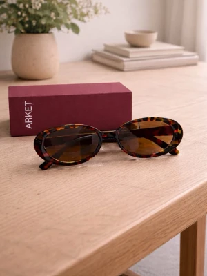 Ovala solglasögon från ARKET - Snygga ovala solglasögon från ARKET med brunmelerat sköldpaddsmönster på bågarna och bruna tonade glas. Trendig retrostil som ger en cool vibe till din outfit. Bågarna är tillverkade i plast och har en smal design.