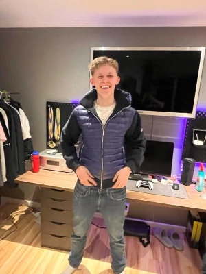 Svart och mörkblå pufferjacka med huva - Snygg pufferjacka i svart och mörkblått med quiltad front och ärmar i kontrastmaterial. Jackan har dragkedja framtill och en stor huva. Perfekt för kyliga dagar och ger en sportig look.